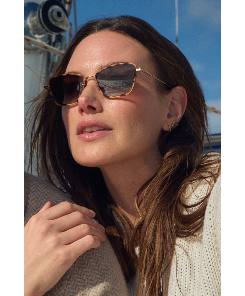 Woman wearing Krewe sunglasses with a sailboat in the background