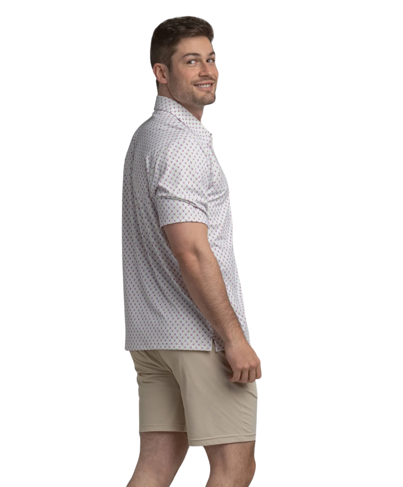 Man wearing a transfusion patterned Southern Shirt Co polo shirt and beige shorts on a white background
