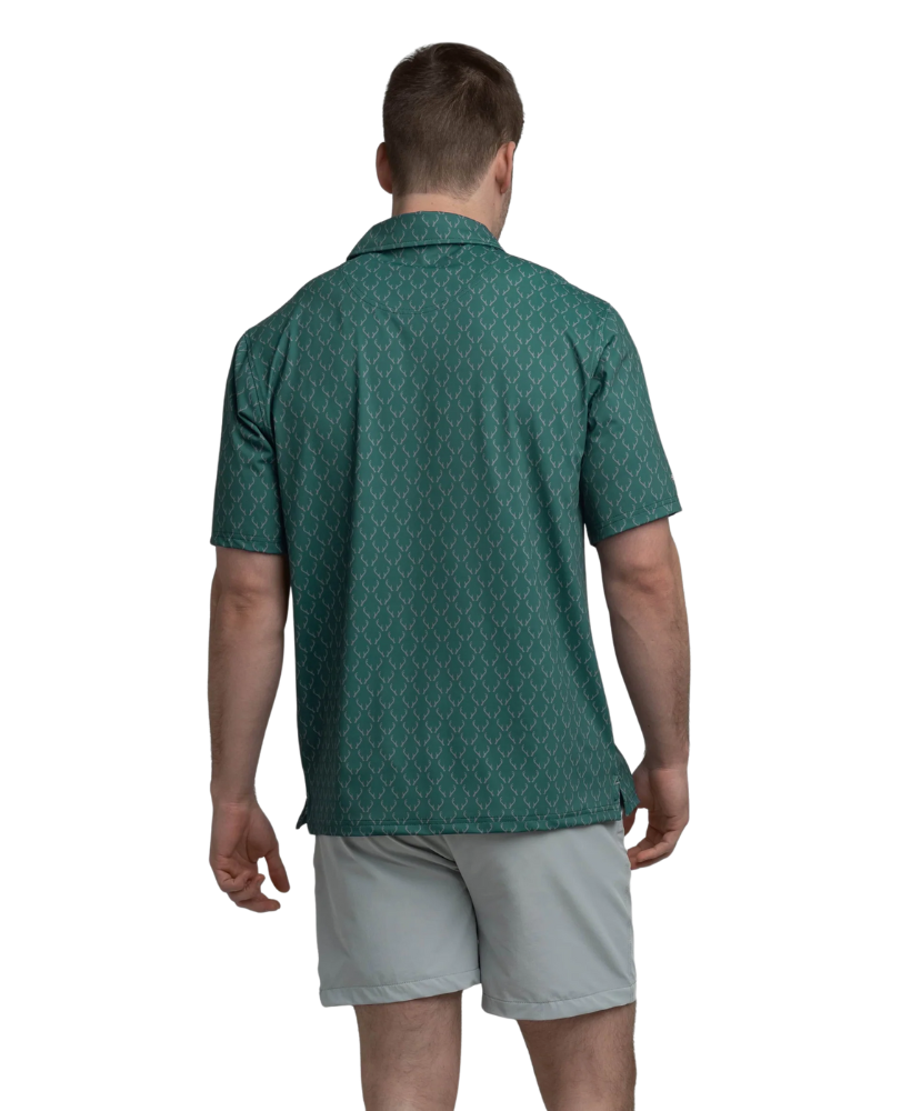Man wearing a Green polo shirt with deer antler pattern and light gray shorts on a white background