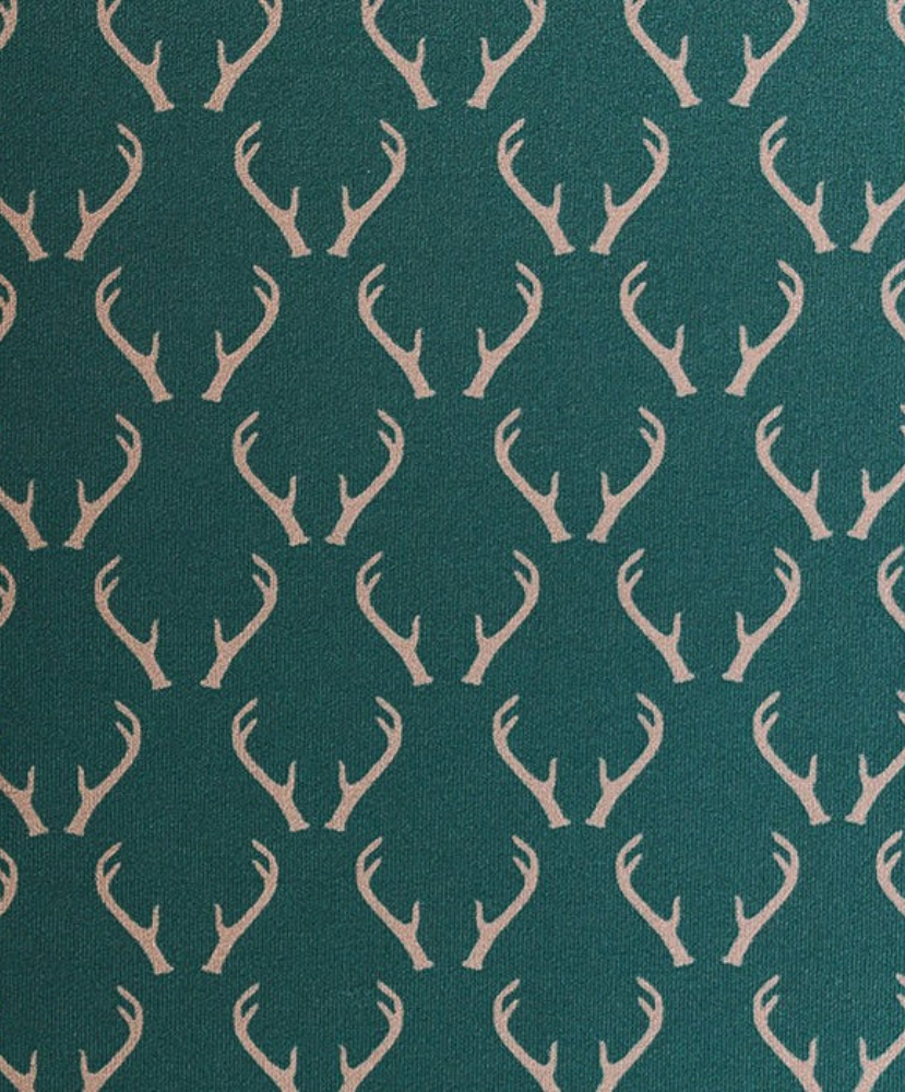 Green polo shirt with deer antler pattern and light gray shorts on a white background