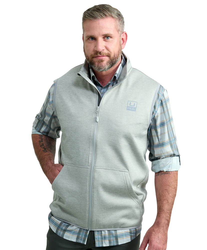 Man wearing a light gray vest WITH ZIPPER over a plaid shirt on a white background HUK GEAR