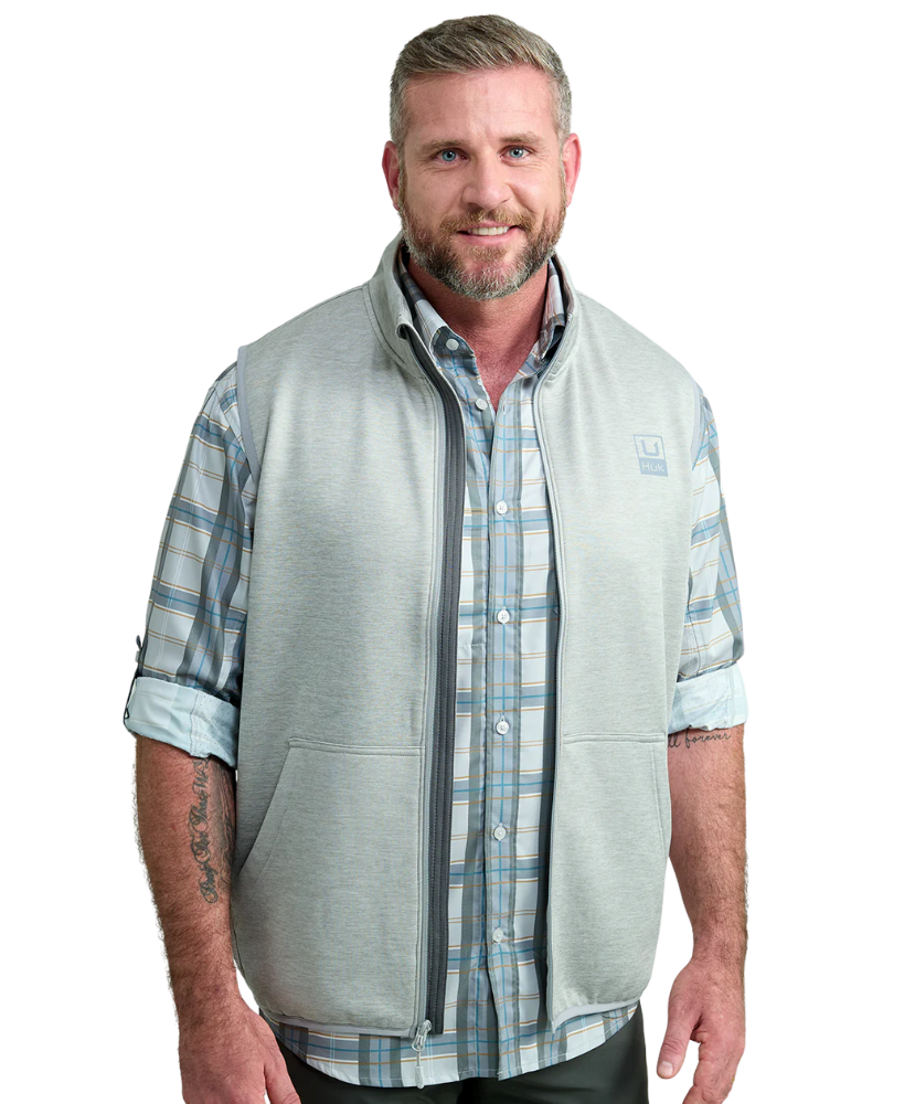 Man wearing a light gray vest WITH ZIPPER over a plaid shirt on a white background HUK GEAR