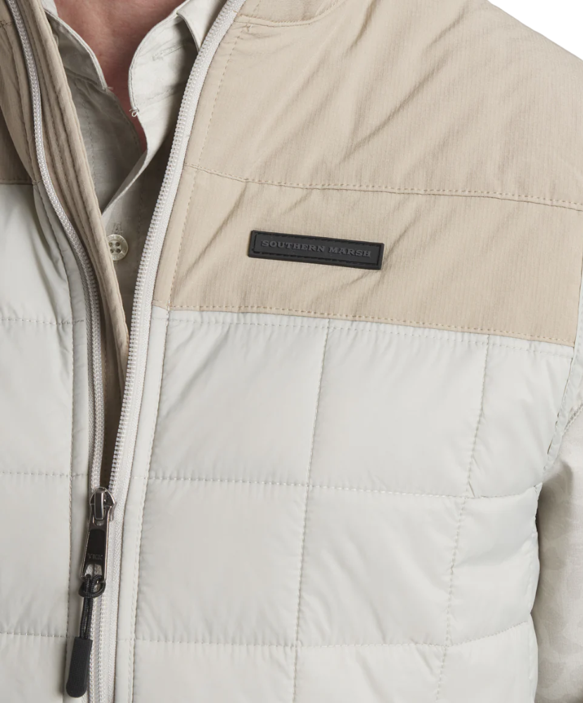 Close-up of a beige and white vest with a Southern Marsh brand logo on a light gray background