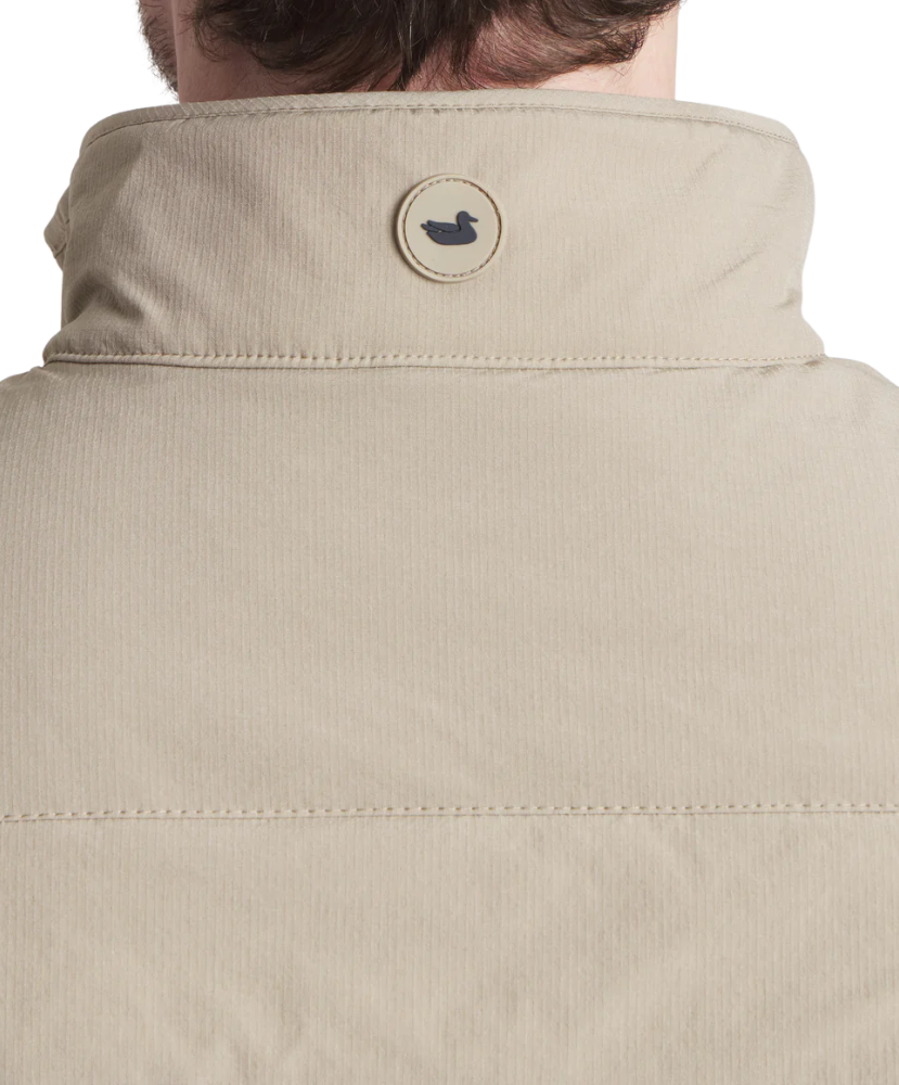 Close-up of a beige jacket with a brand logo on the collar against a white background