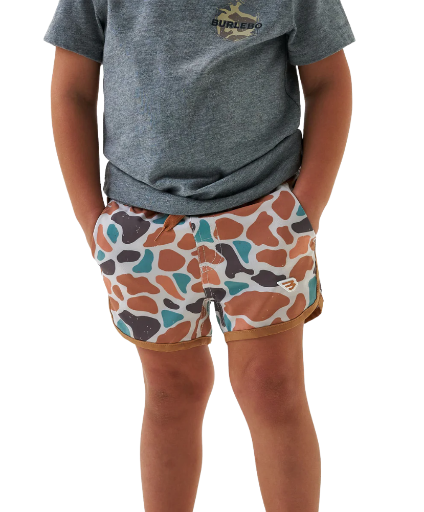 Child wearing a gray t-shirt and camo patterned swim shorts on a white background