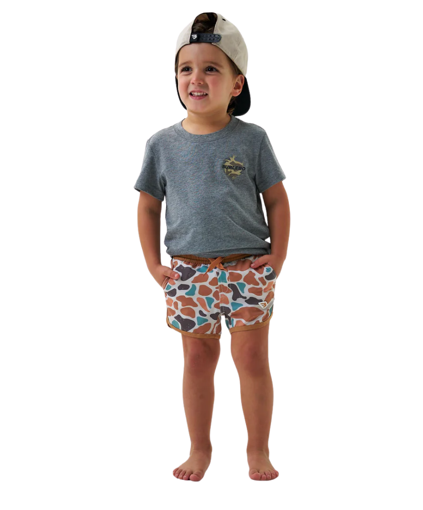 Child wearing a gray t-shirt and camo patterned swim shorts on a white background