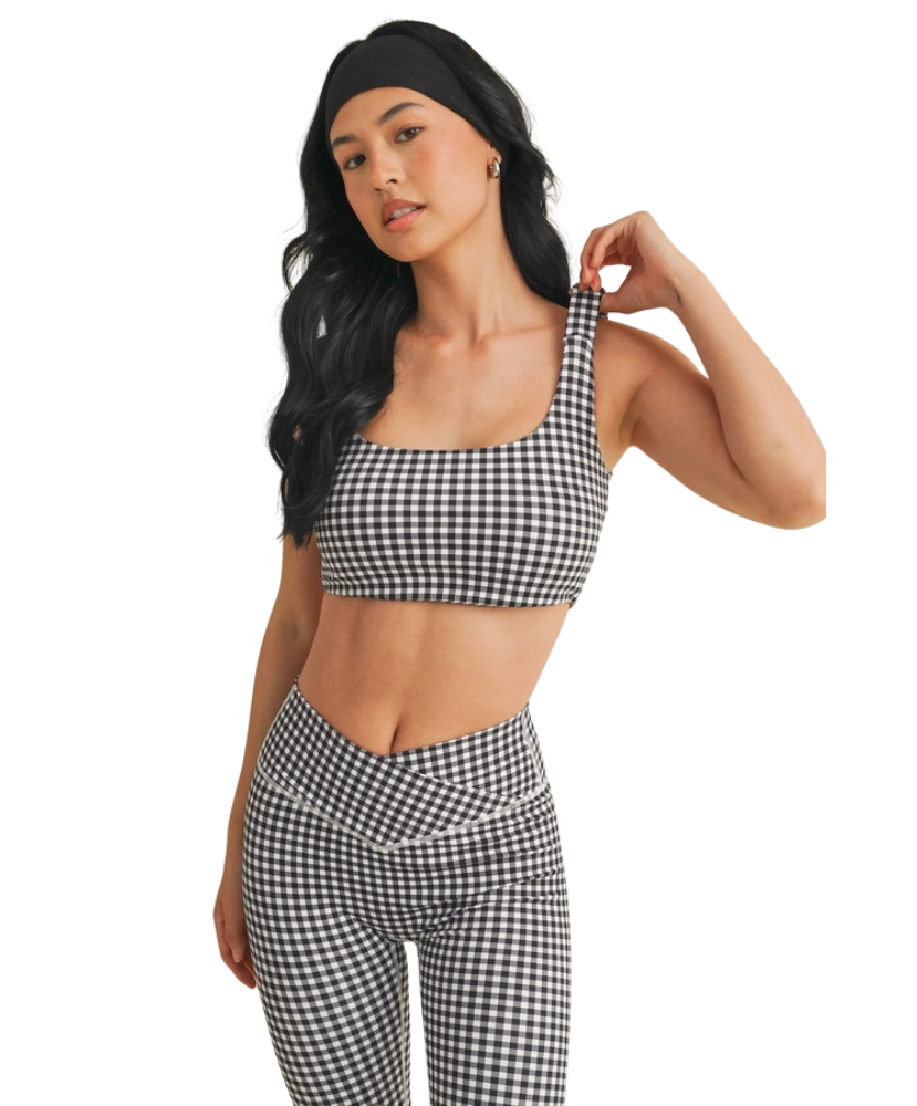 Woman wearing a black and white GINGHAM checkered tsports bra on a white backgrounD