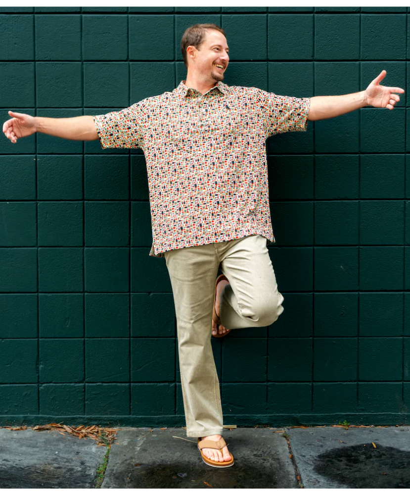 Man with arms outstretched against a green tiled wall