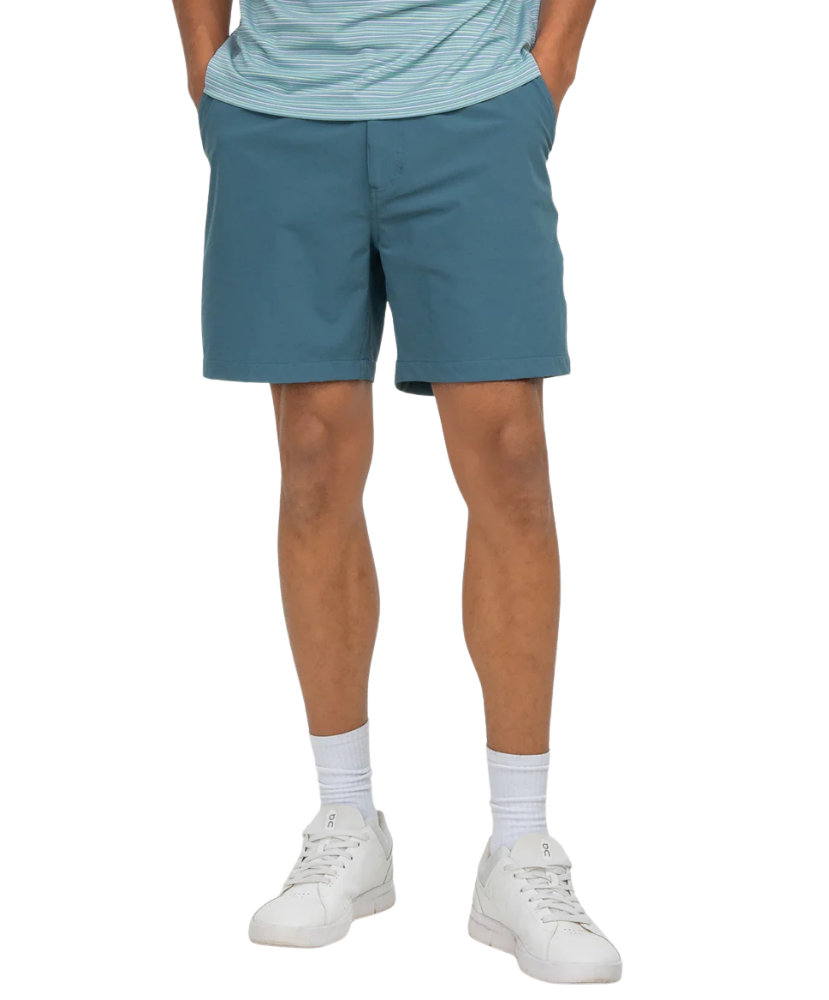 Person wearing teal shorts and white sneakers on a white background