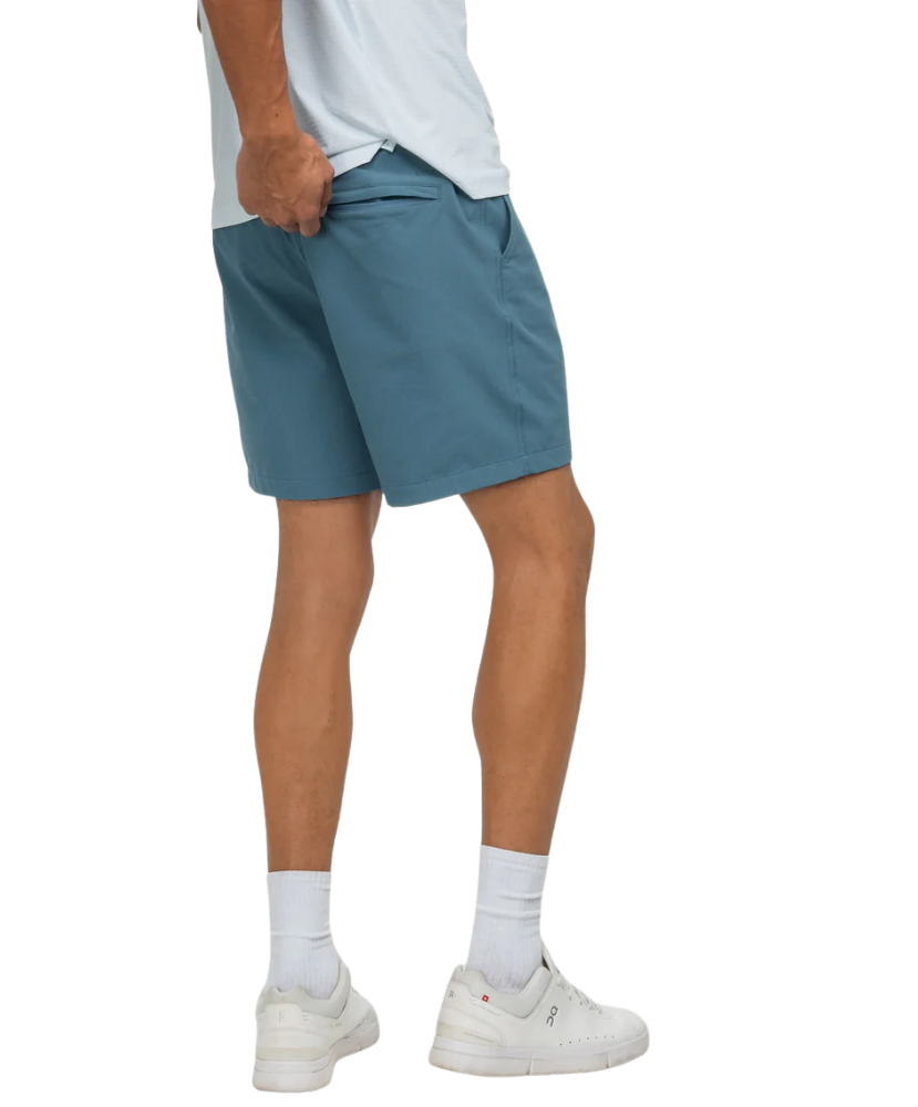 Person wearing blue shorts and white sneakers on a white background
