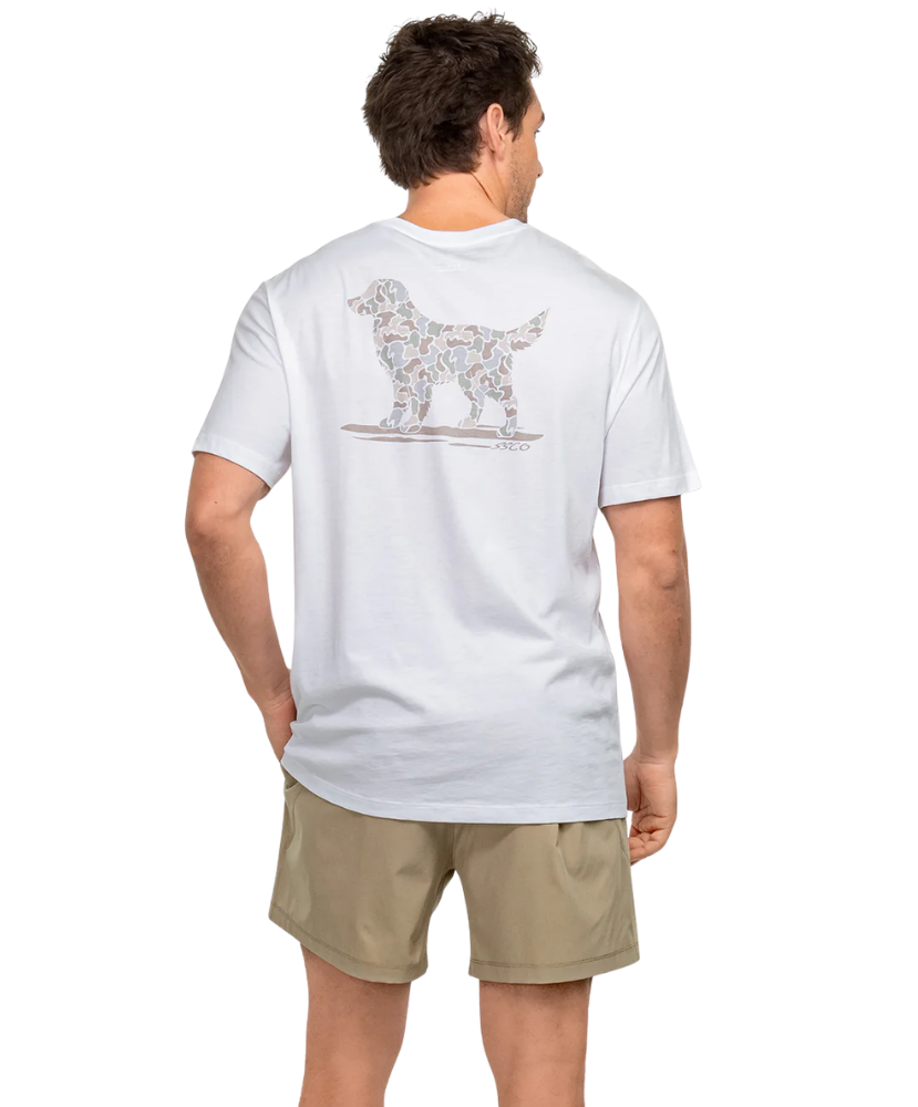 Man wearing a white t-shirt with a CAMO dog graphic on the back, standing against a white background