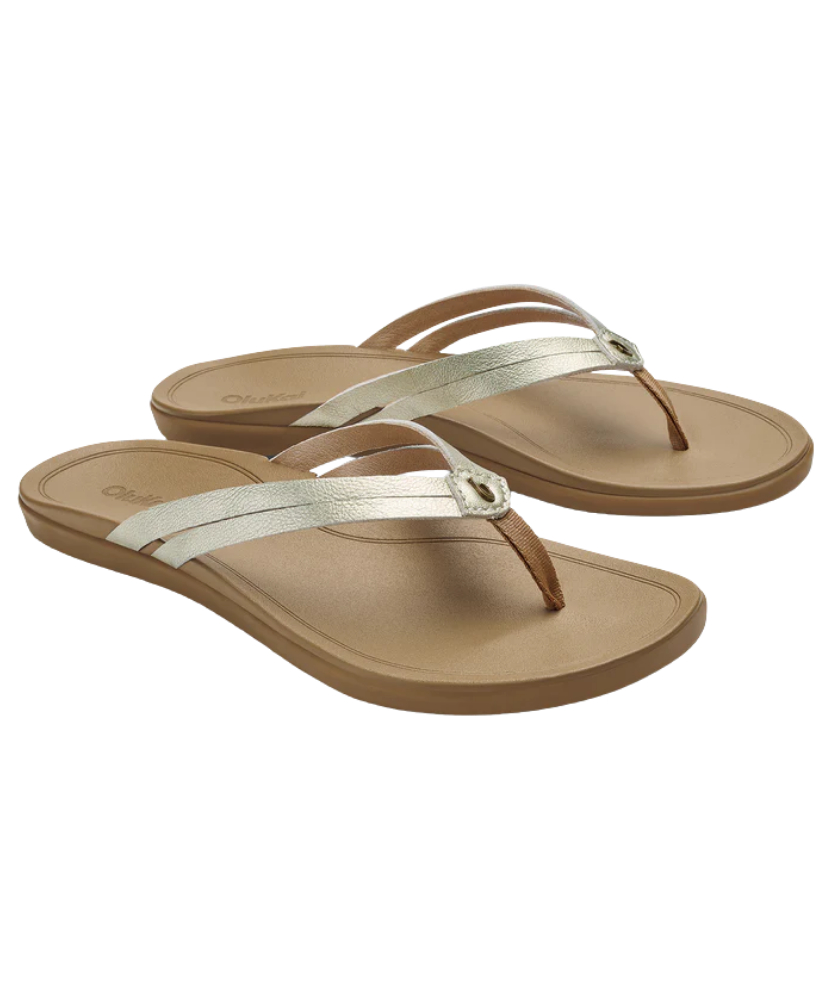 Pair of tan OLUKAI sandals with silver straps on a white background