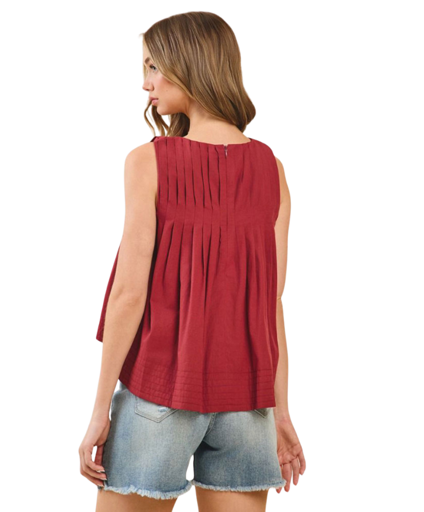 Woman wearing a burgundy sleeveless top and denim shorts on a white background