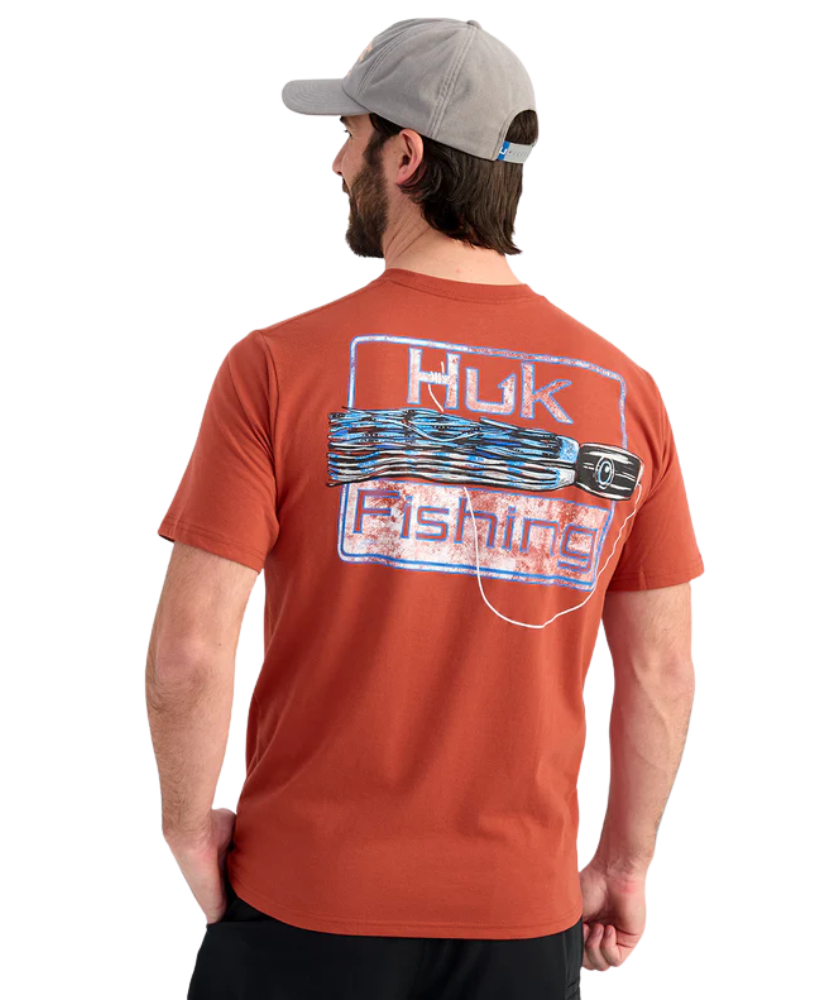 Man wearing an RED Huk Fishing t-shirt with a fishing lure logo on the back against a white background