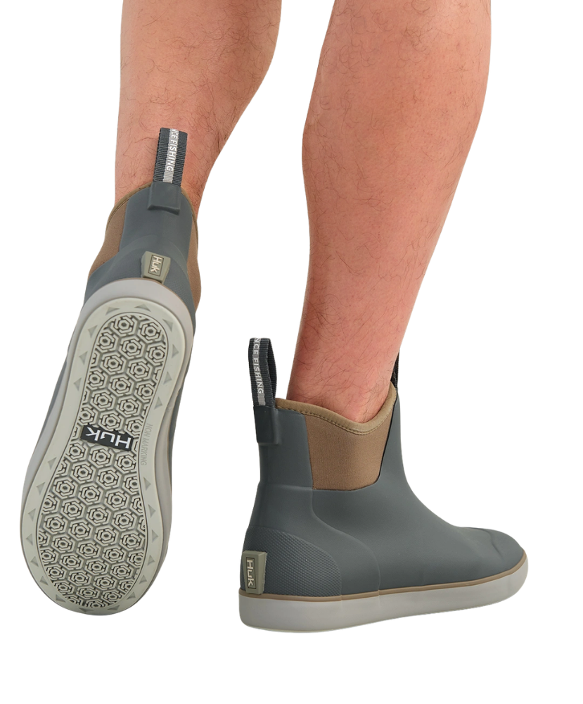 A pair of HUK ankle-height water shoes shown on a model's feet against a white background, displaying the side profile, sole tread, and heel pull tab.