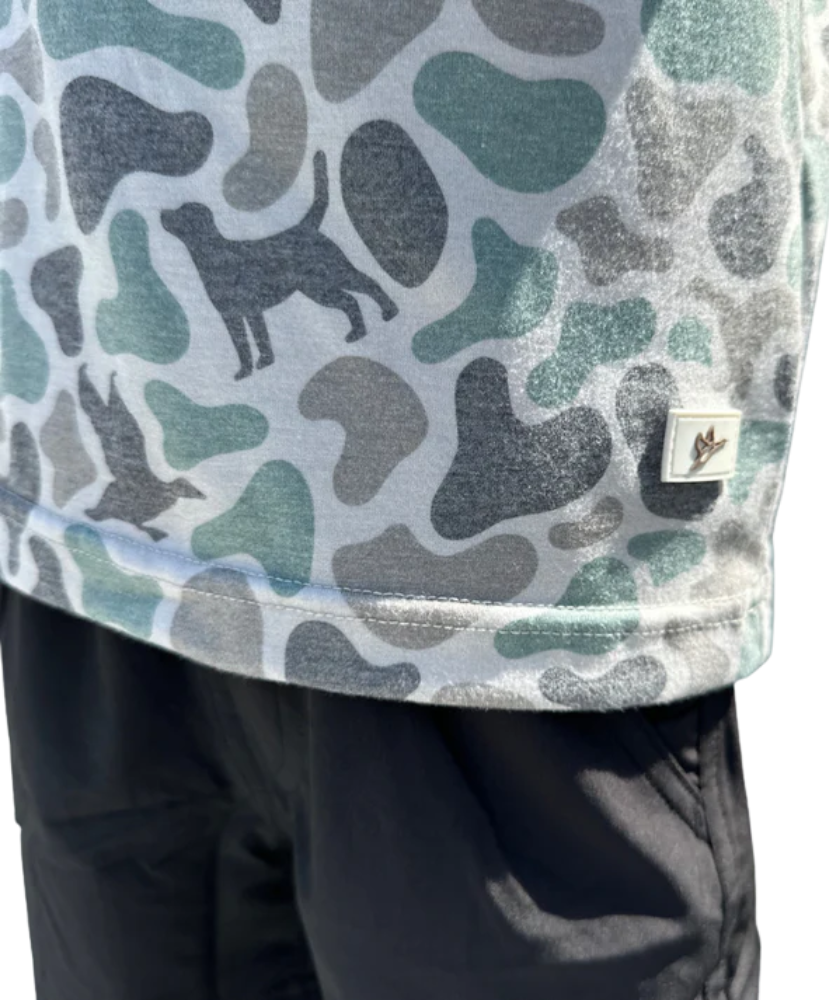 Camouflage-patterned shirt with a brand logo on a person wearing dark pants.