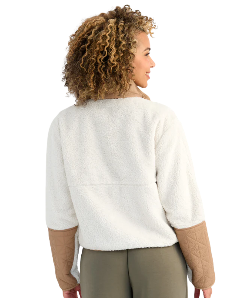 Woman wearing a white and beige fleece pullover on a white background