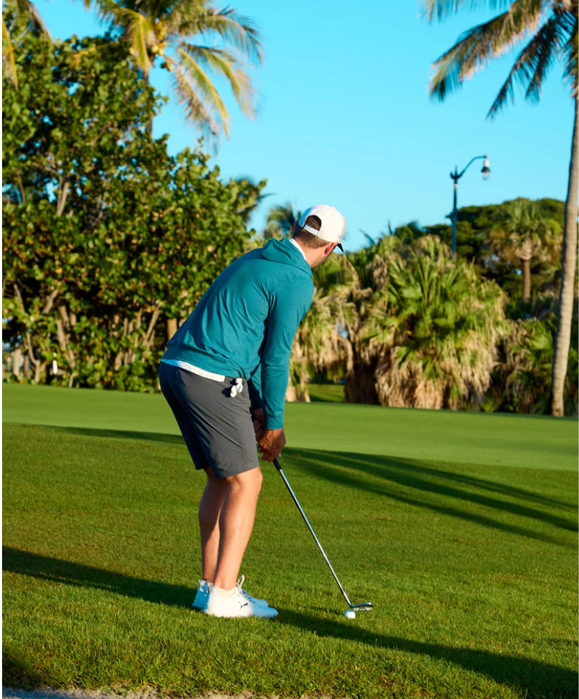Person playing golf on a sunny day with palm trees in the background