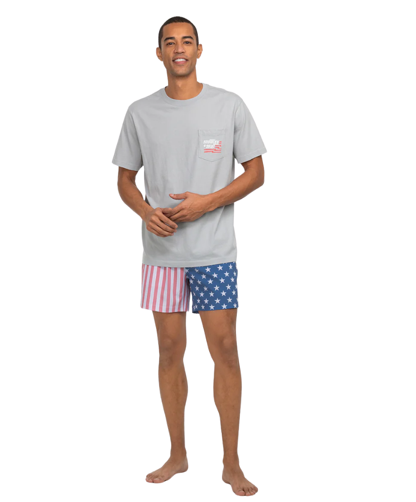 Man wearing a gray t-shirt and American flag shorts on a white background