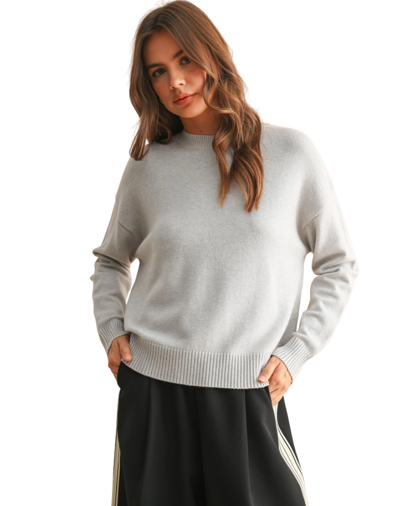 Woman wearing a light gray sweater and black skirt on a white background