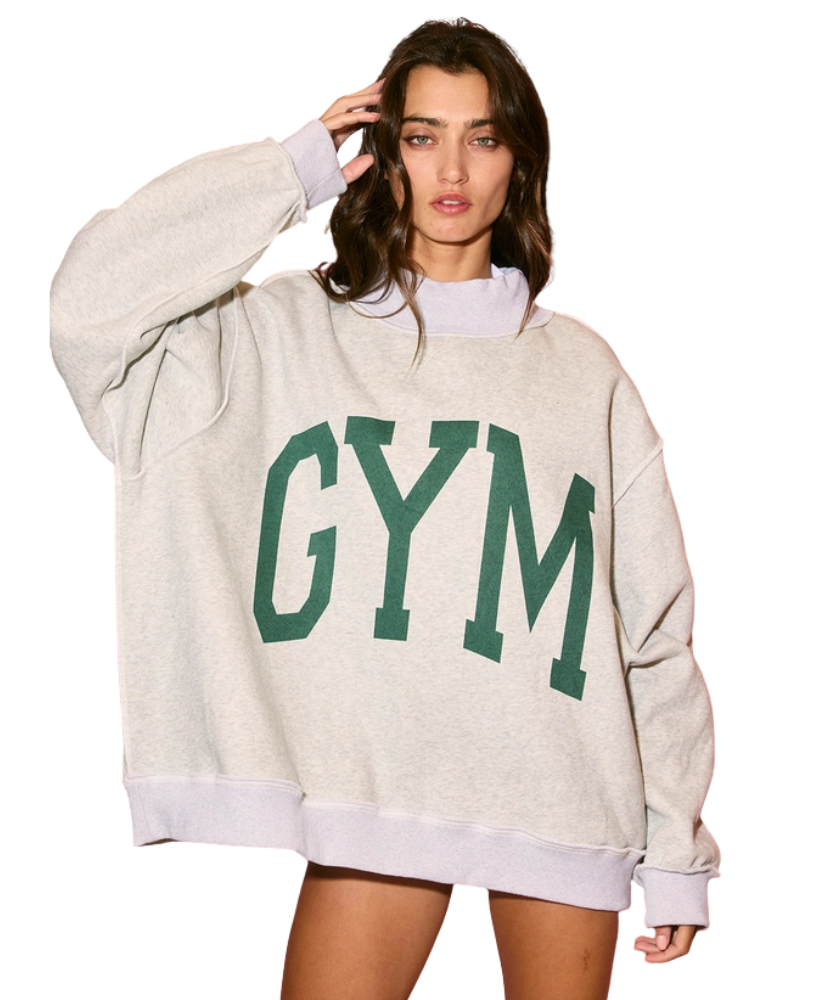 Woman wearing a beige sweatshirt with 'GYM' printed in green on a white background