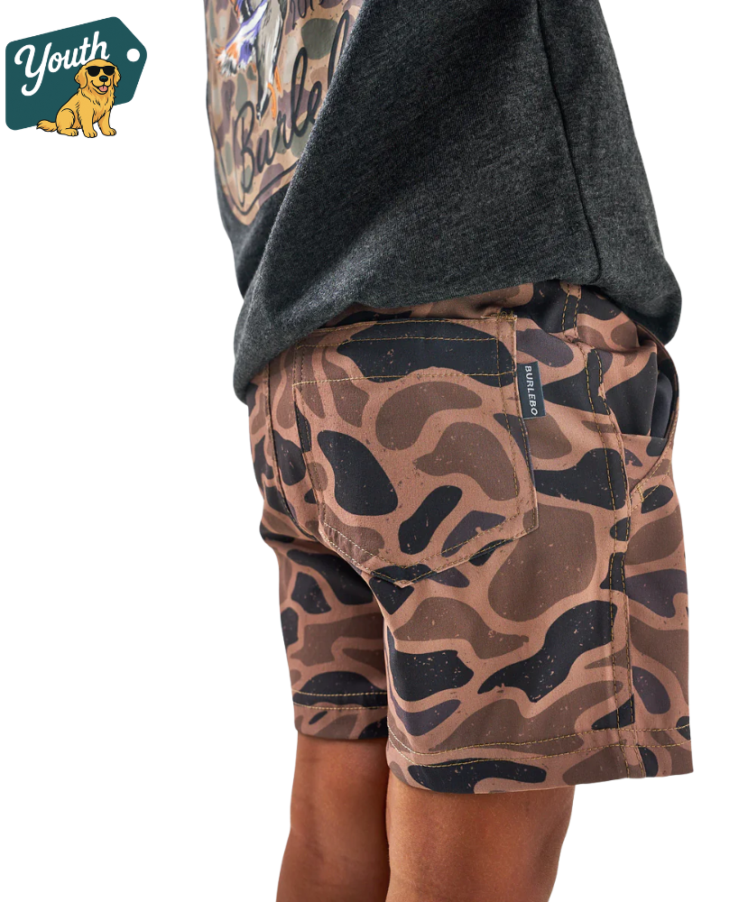 Camouflage shorts worn by a person with a brand logo in the corner.