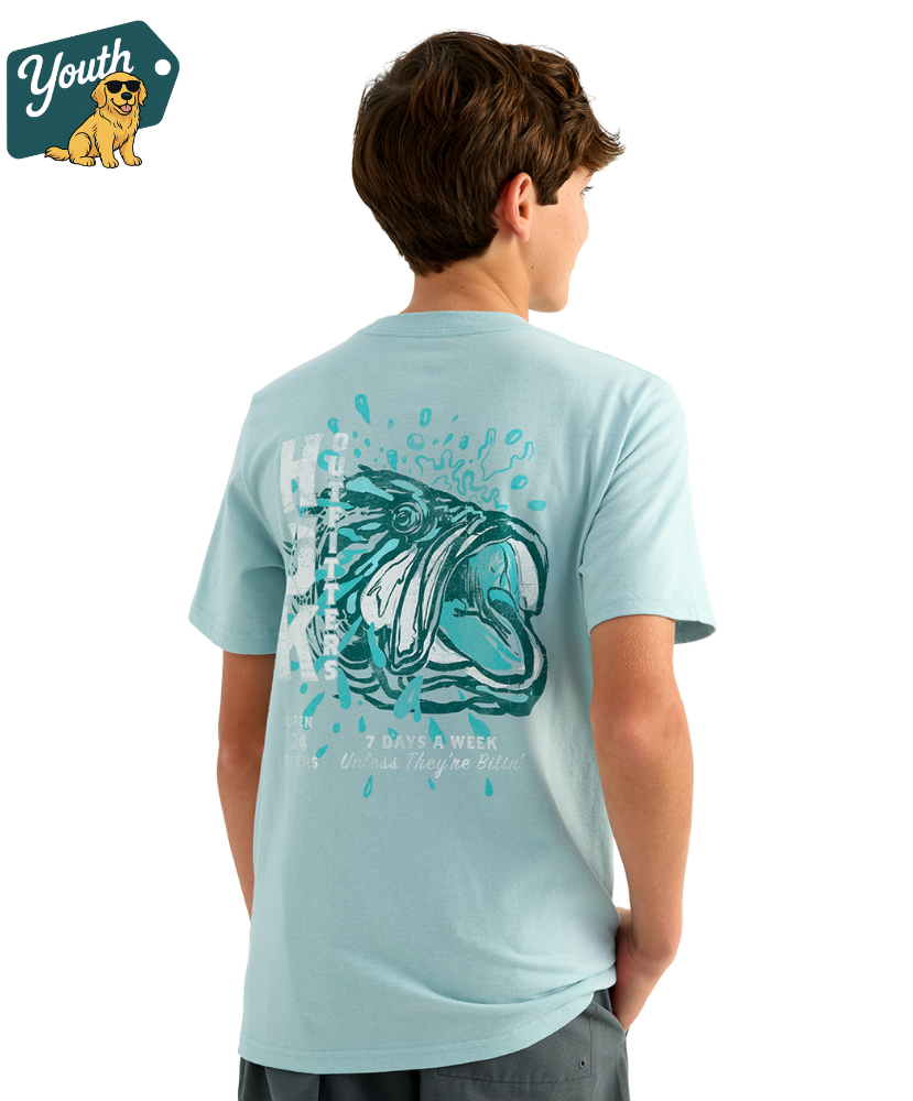 KID wearing a light blue HUK t-shirt with a bass design on the back, standing against a white background.