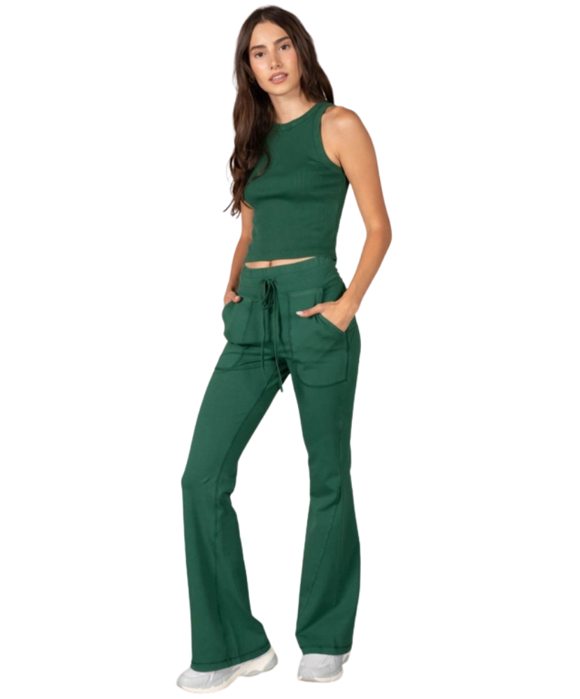 Woman wearing a green tank and pants athleisure set outfit on a white background