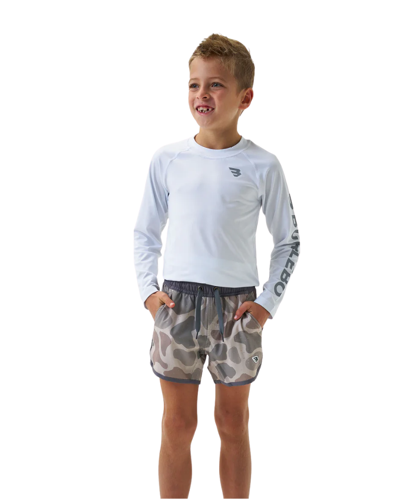 Child wearing a white long-sleeve shirt and camouflage shorts on a white background