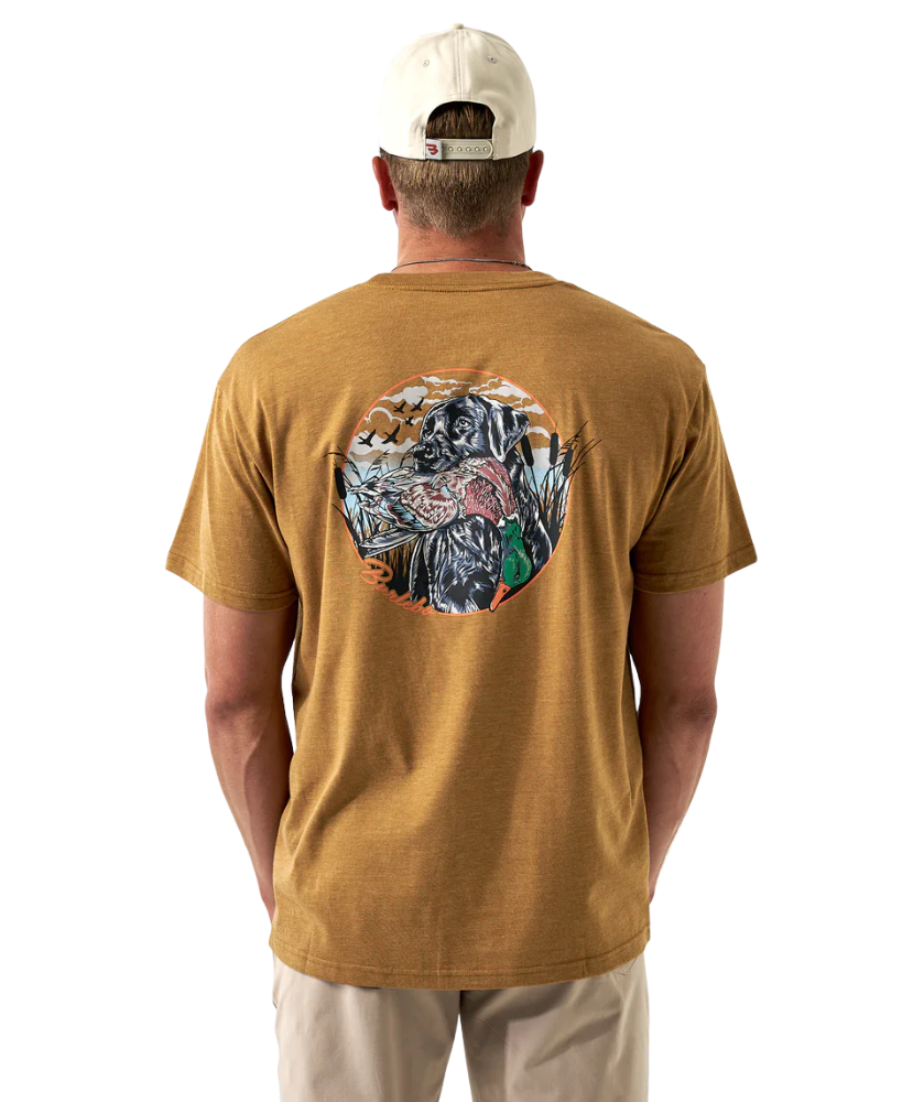 Man wearing a light brown t-shirt with a colorful dog and duck design on the back, standing against a white background.