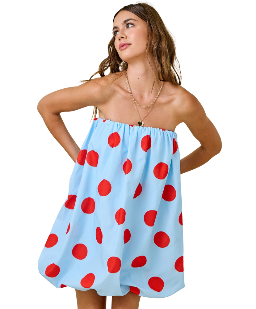 Woman wearing a light blue dress with red polka dots on a white background