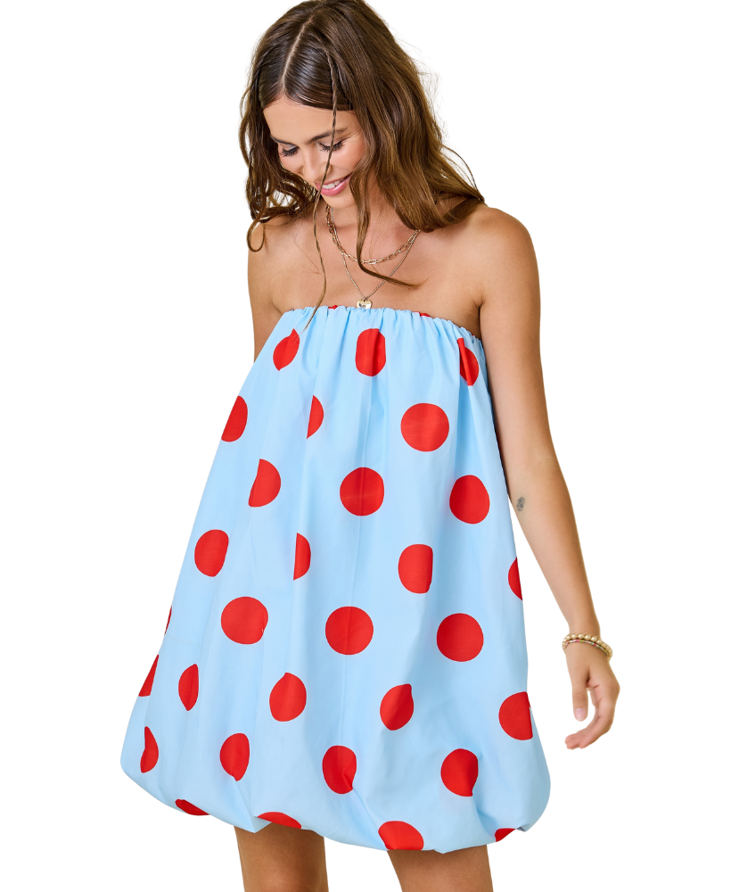 Woman wearing a strapless dress with red polka dots on a white background