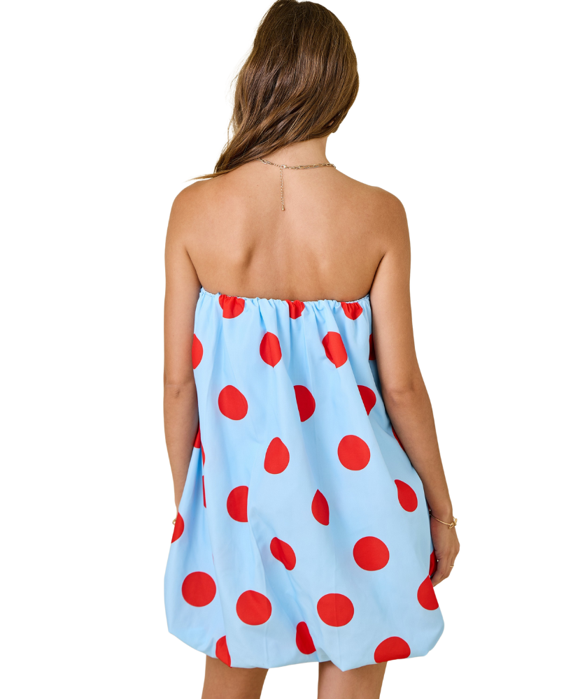 Woman wearing a strapless dress with red polka dots on a white background