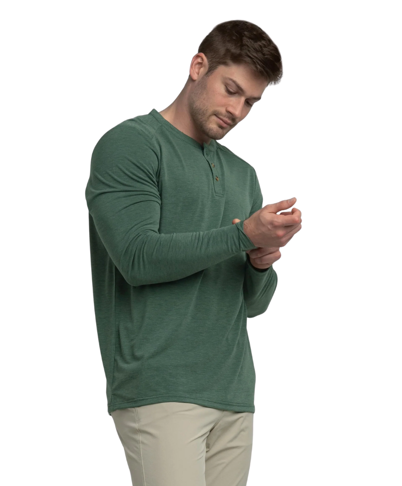 Man wearing a green long-sleeve henley shirt and beige pants on a white background