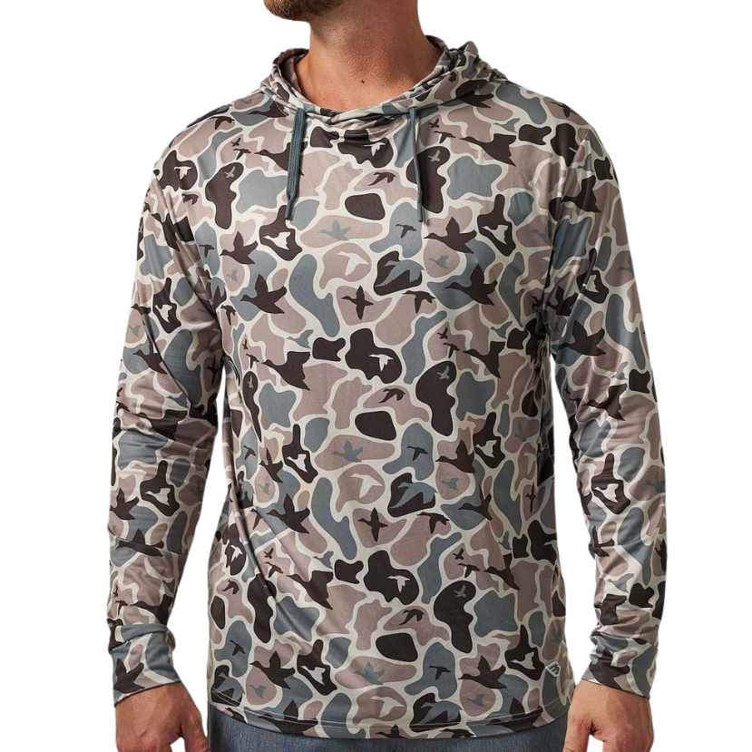 A man wearing a long-sleeve camouflage hoodie in shades of gray, beige, and black, paired with blue jeans, shown from the waist up against a plain white background.