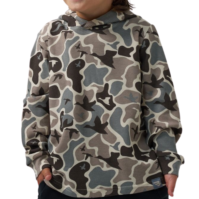 A child wearing a waffle-knit hoodie with a muted camouflage pattern in beige, gray, and black, paired with dark pants against a plain white background.