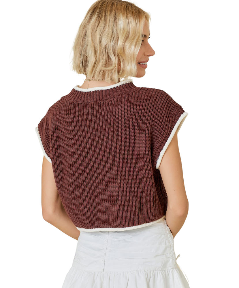 Woman wearing a brown knitted vest with white trim on a white background