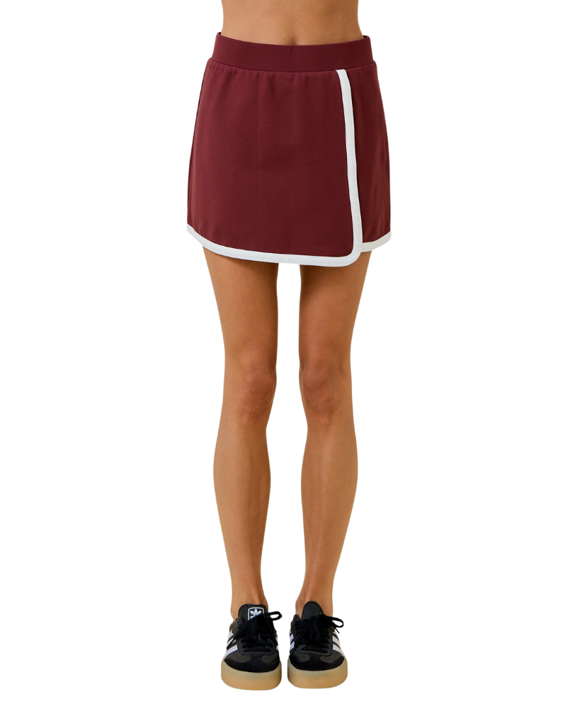 Maroon athletic skirt with white stripe worn by a person on a white background