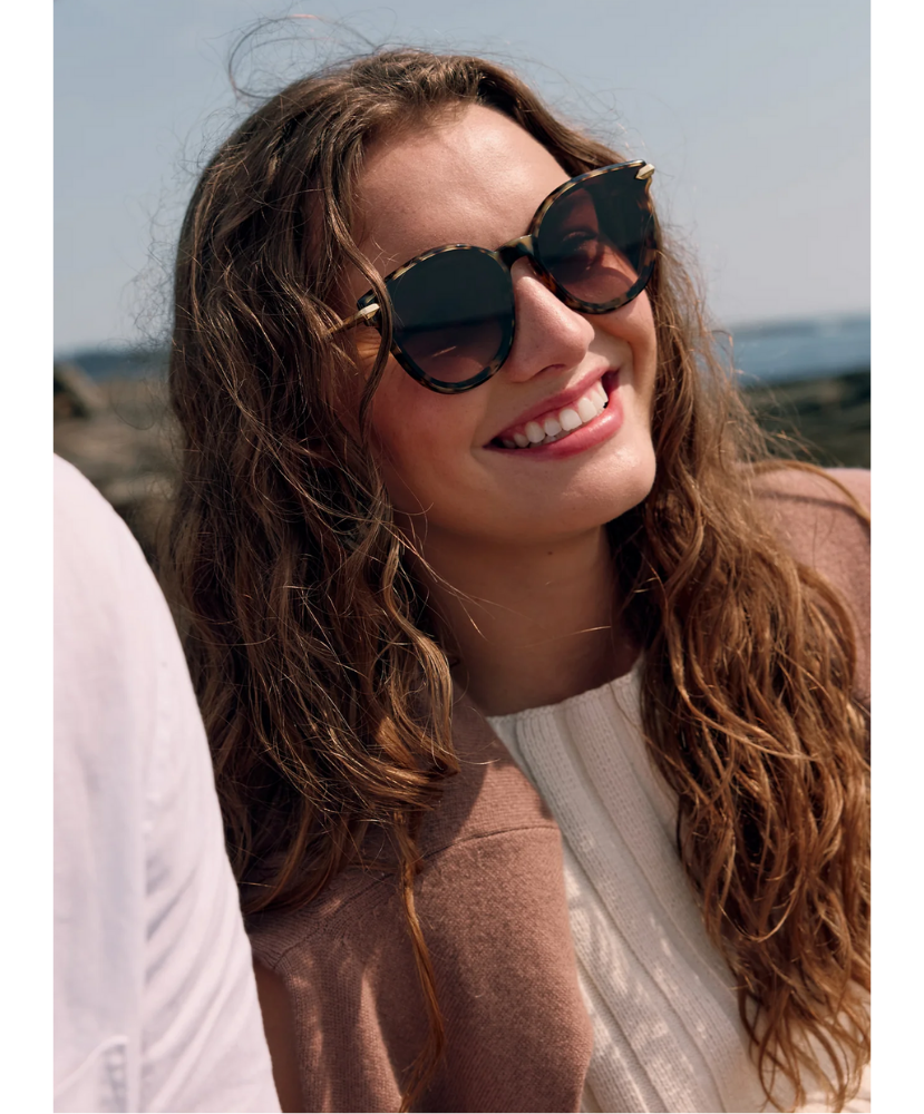 Woman wearing Krewe sunglasses with a scenic background