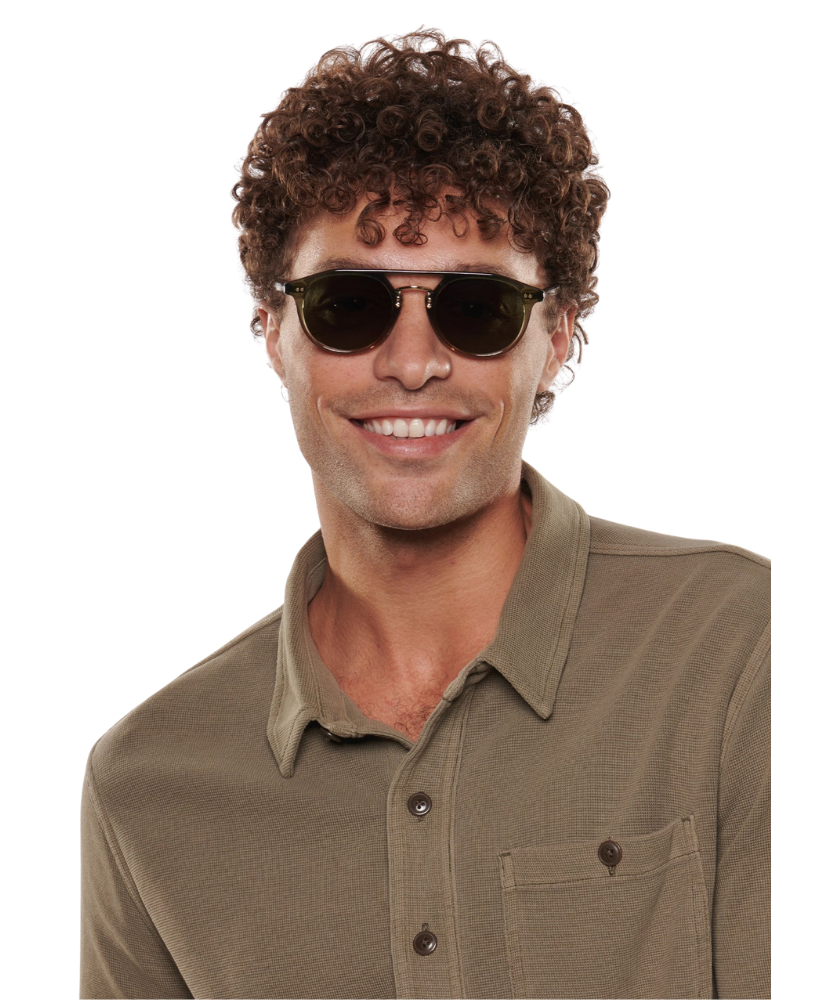 Man wearing Krewe Markle sunglasses and a brown shirt on a white background