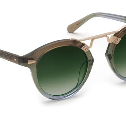 A pair of Krewe sunglasses with a St. Louis frame design, featuring a round full frame with a patterned tortoise shell appearance and 24K gold plated hardware.