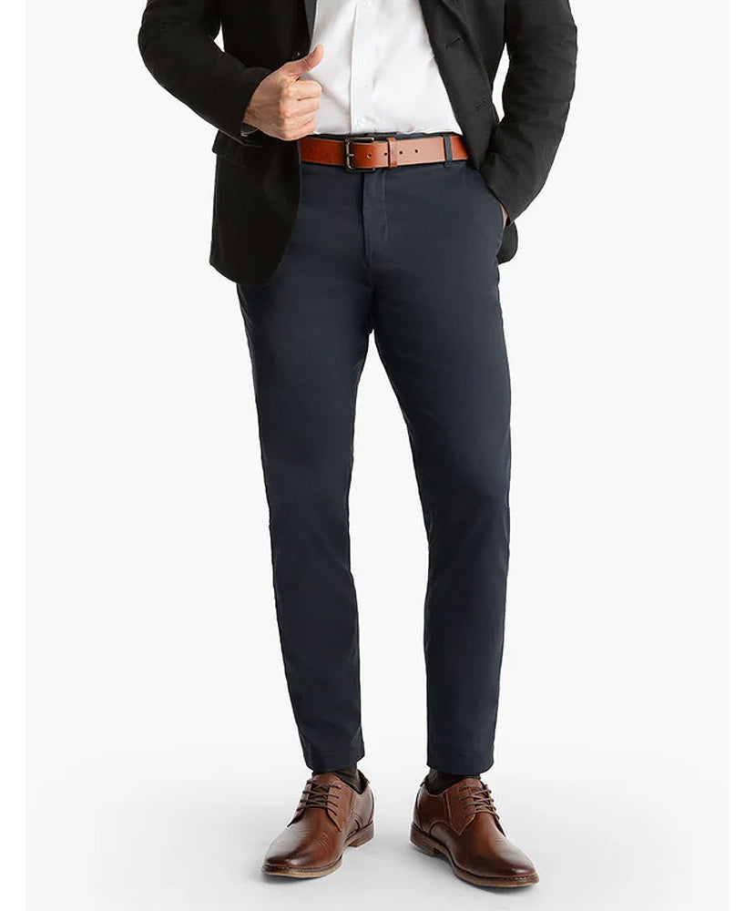 Person wearing a black blazer, white shirt, navy pants, and brown shoes on a white background