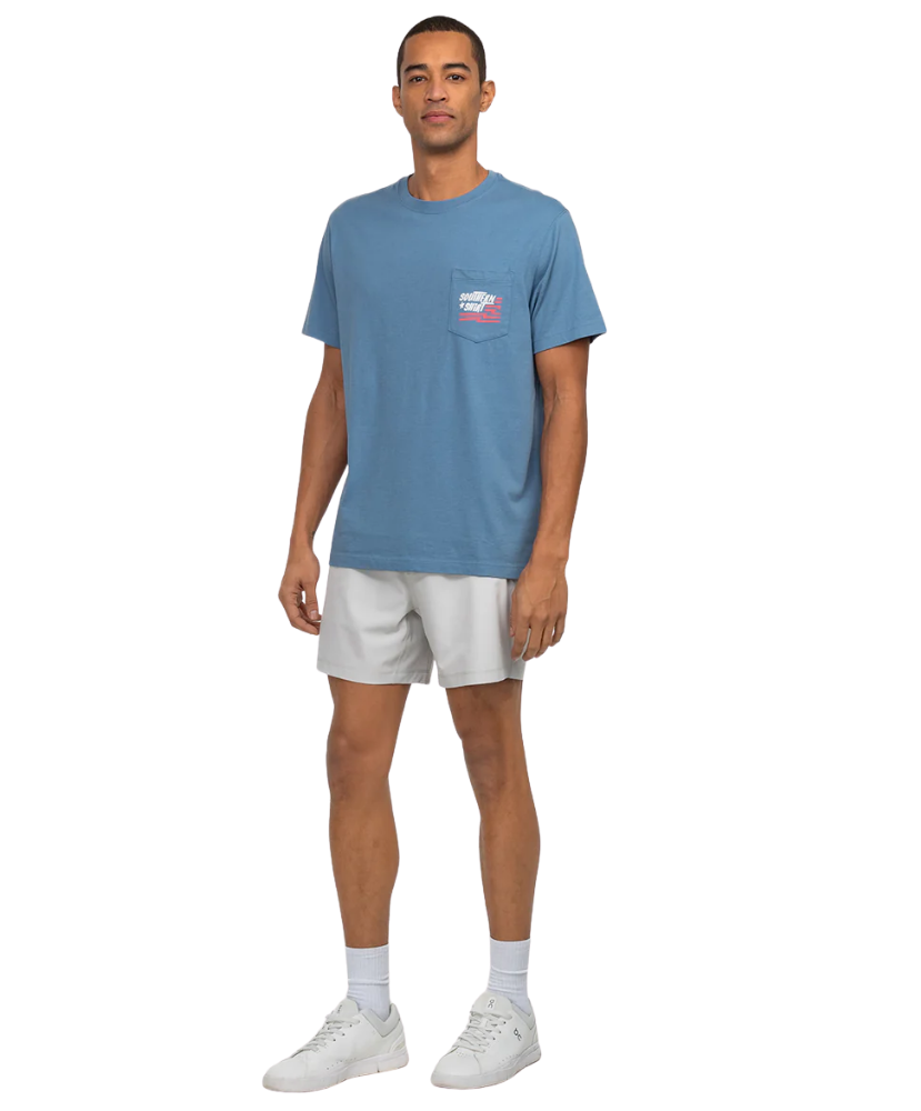 Man wearing a blue t-shirt with a logo and white shorts on a white background