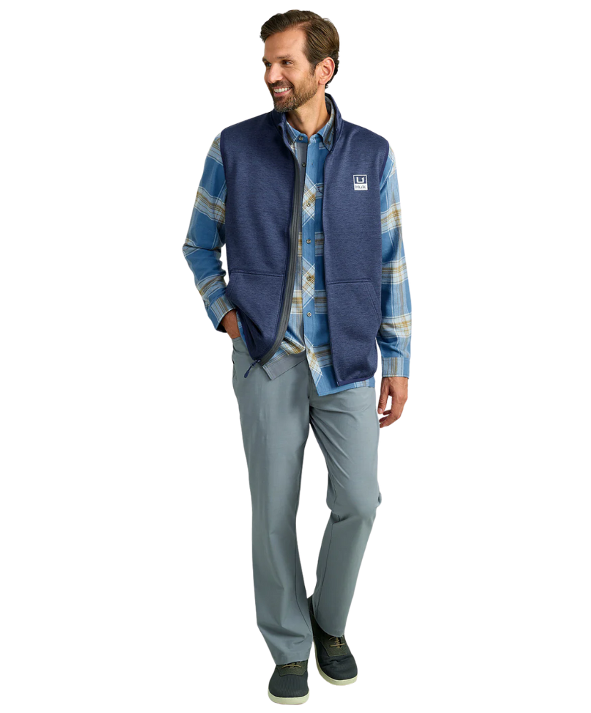 Man wearing a blue fleece vest over a plaid shirt on a white background HUK GEAR VEST