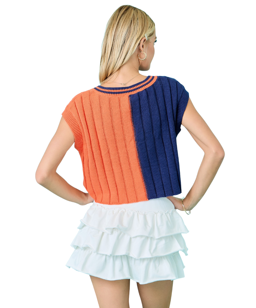 Woman wearing a two-tone orange and blue sweater with a white skirt on a white background