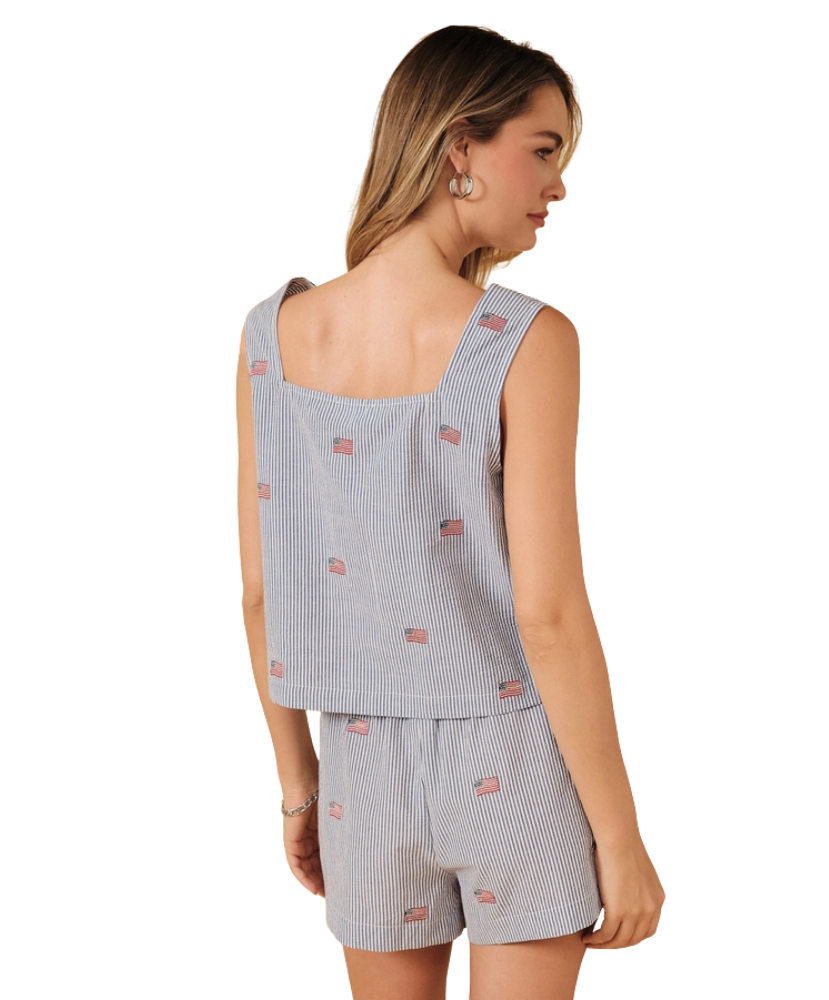 Woman wearing a light blue sleeveless top and shorts with small USA flag patterns on a white background