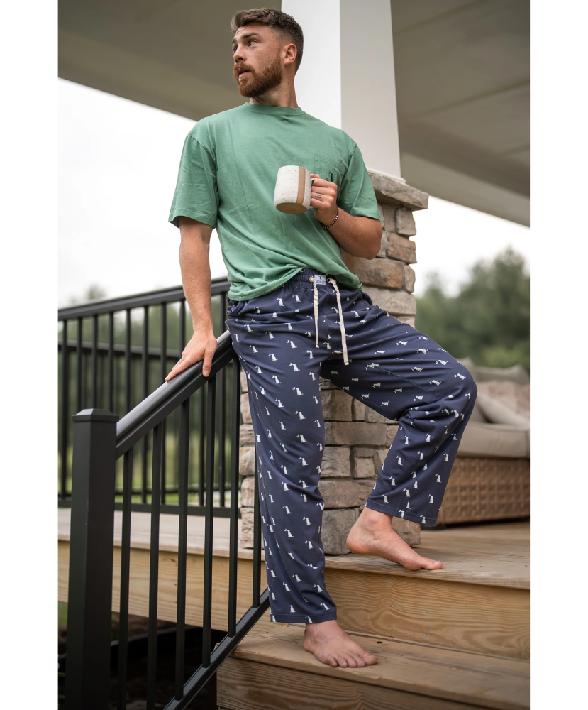 Man navy pajama pants holding a mug on a deck.
