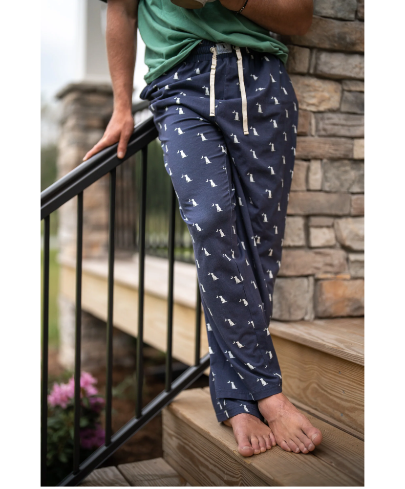 Person wearing navy blue pajama pants with a dog pattern, standing on a staircase.