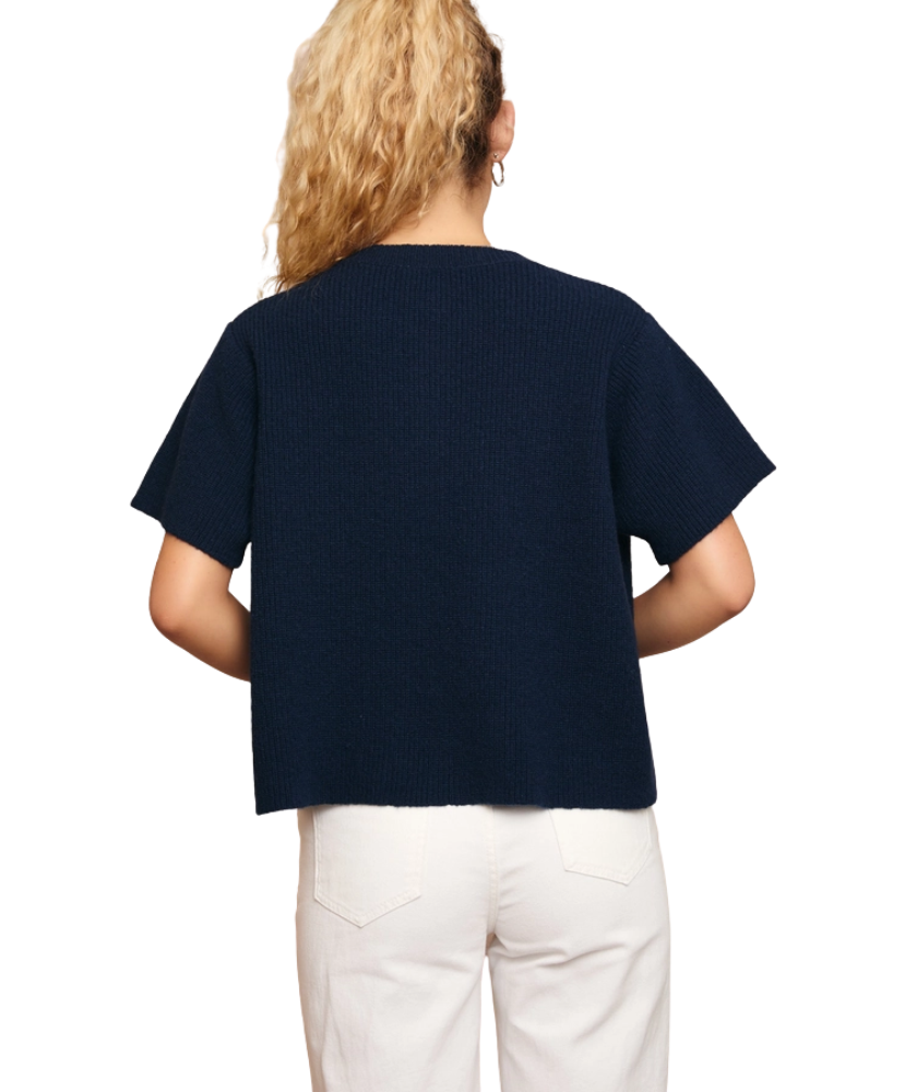 Woman wearing a navy blue sweater and white pants on a white background