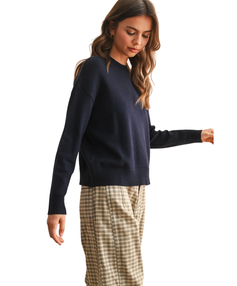 Woman wearing a navy sweater and plaid pants on a white background